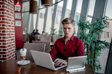 Masada oturan ve dizüstü bilgisayarda çalışan bir adam.