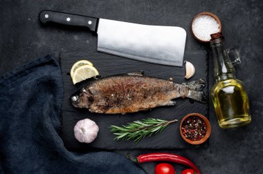 Taş zeminde baharat ve malzemelerle kızarmış balık alabalığı.