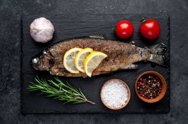 Taş zeminde baharat ve malzemelerle kızarmış balık alabalığı.