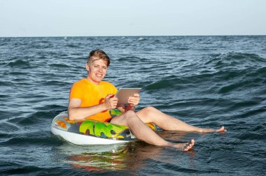 Suda şişme yüzük tabletli bir adam.