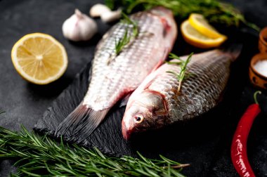 Limonlu ve kekikli Crucian sazan balığı taştan bir arka planda tahta üzerinde. Nehir balığı .