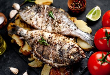Kayalık zeminde kızarmış Dorado balığı ve patates.
