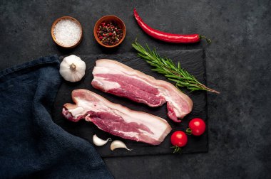 Metnin için fotokopi alanı olan taştan bir arka planda kesilmiş baharatlı çiğ domuz göğsü.