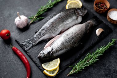 Taş zeminde baharat ve malzemelerle çiğ balık alabalığı.