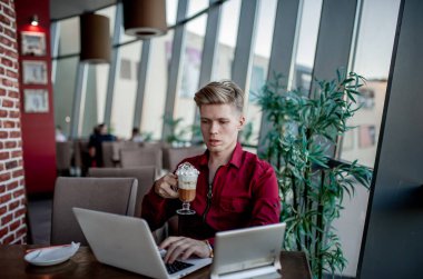 Masada oturan ve dizüstü bilgisayarda çalışan bir adam.