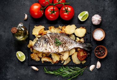 Kayalık zeminde kızarmış Dorado balığı ve patates.