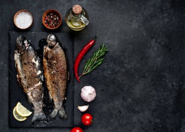 Taş zeminde baharat ve malzemelerle kızarmış balık alabalığı.