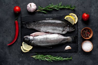 Taş zeminde baharat ve malzemelerle çiğ balık alabalığı.