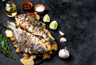 Kayalık zeminde kızarmış Dorado balığı ve patates.