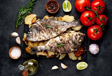 Kayalık zeminde kızarmış Dorado balığı ve patates.