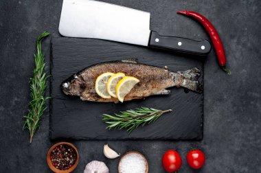 Taş zeminde baharat ve malzemelerle kızarmış balık alabalığı.