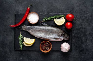 Taş zeminde baharat ve malzemelerle çiğ balık alabalığı.