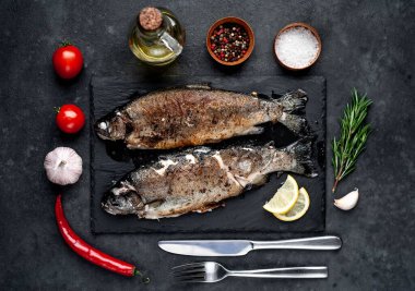 Taş zeminde baharat ve malzemelerle kızarmış balık alabalığı.