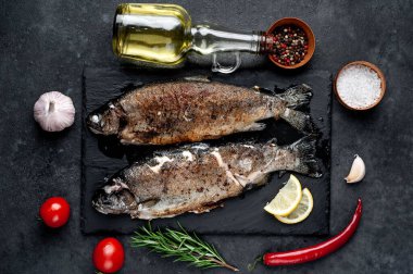 Taş zeminde baharat ve malzemelerle kızarmış balık alabalığı.