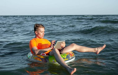 Suda şişme yüzük tabletli bir adam.