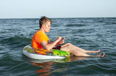 Suda şişme yüzük tabletli bir adam.