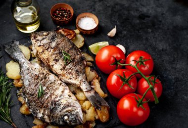 Kayalık zeminde kızarmış Dorado balığı ve patates.