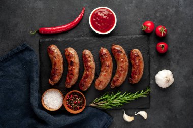 Bir taş zemin üzerinde baharatlı ızgara sosisler ve metin için kopyalama alanı.