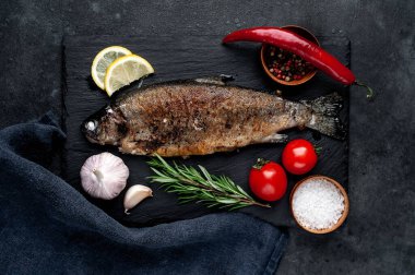 Taş zeminde baharat ve malzemelerle kızarmış balık alabalığı.