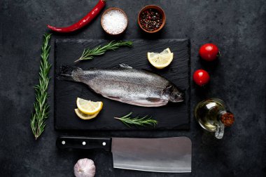 Taş zeminde baharat ve malzemelerle çiğ balık alabalığı.