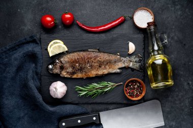 Taş zeminde baharat ve malzemelerle kızarmış balık alabalığı.