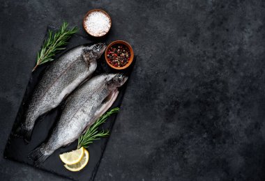 Taş zeminde baharat ve malzemelerle çiğ balık alabalığı.