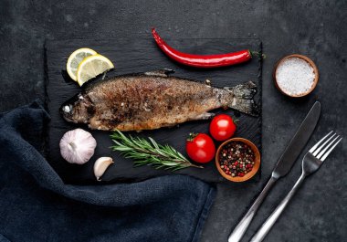 Taş zeminde baharat ve malzemelerle kızarmış balık alabalığı.