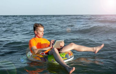 Suda şişme yüzük tabletli bir adam.