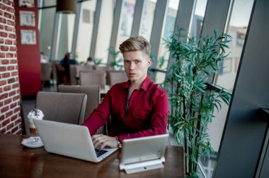 Masada oturan ve dizüstü bilgisayarda çalışan bir adam.