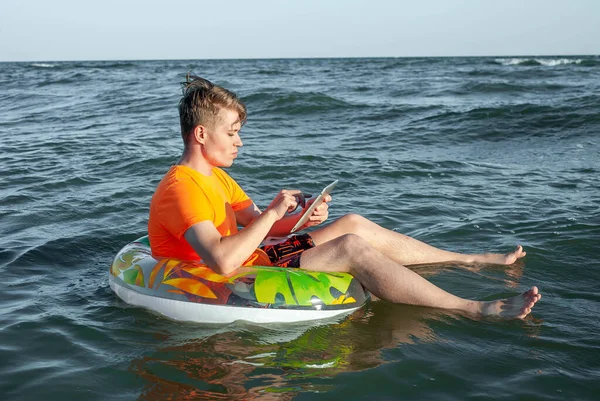 Suda şişme yüzük tabletli bir adam.