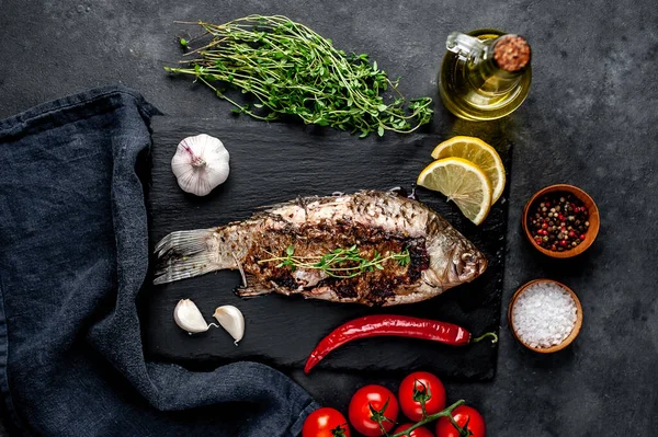 Limonlu ve biberiyeli sazan balığı. Taş zeminde bir tahta üzerinde.