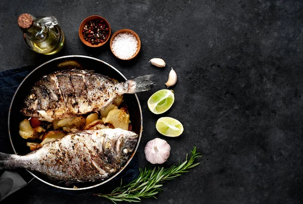 Kayalık zeminde kızarmış Dorado balığı ve patates.