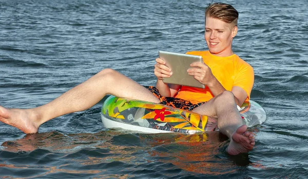 Suda şişme yüzük tabletli bir adam.