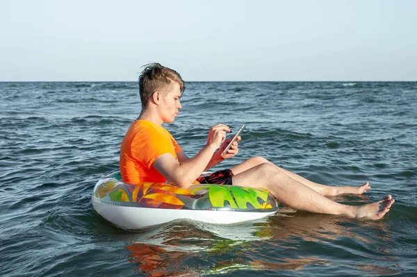 Suda şişme yüzük tabletli bir adam.