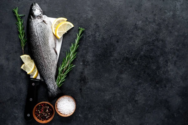 raw fish trout with spices and ingredients on a stone background