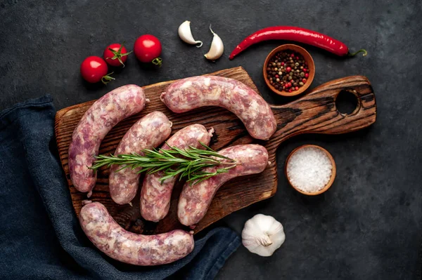 Izgara için çiğ sosis ve arka plandaki kesme tahtasındaki baharatlar.