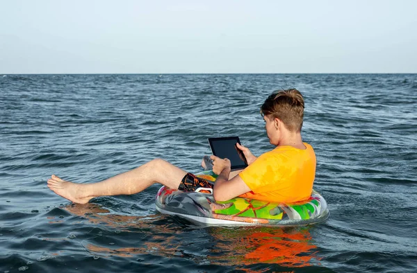 Suda şişme yüzük tabletli bir adam.