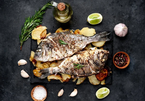 Kayalık zeminde kızarmış Dorado balığı ve patates.