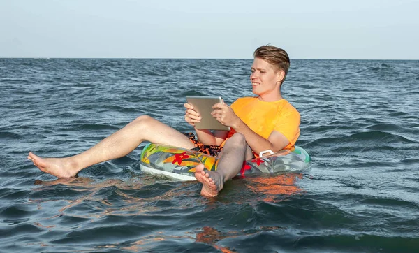 Suda şişme yüzük tabletli bir adam.