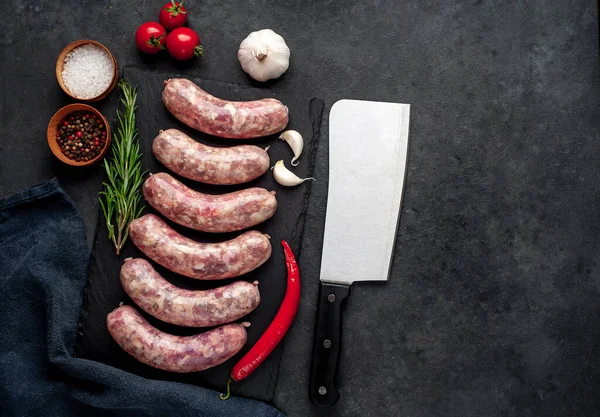 Izgara için çiğ sosis ve arka plandaki kesme tahtasındaki baharatlar.