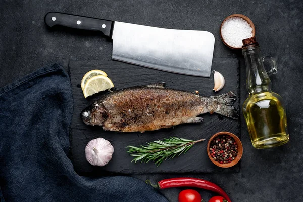 Taş zeminde baharat ve malzemelerle kızarmış balık alabalığı.
