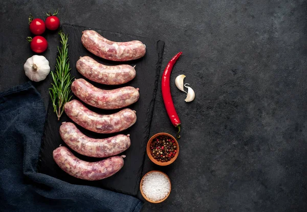Izgara için çiğ sosis ve arka plandaki kesme tahtasındaki baharatlar.
