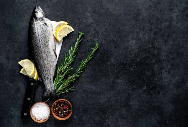 Taş zeminde baharat ve malzemelerle çiğ balık alabalığı.