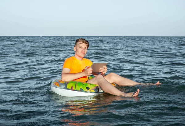 Suda şişme yüzük tabletli bir adam.