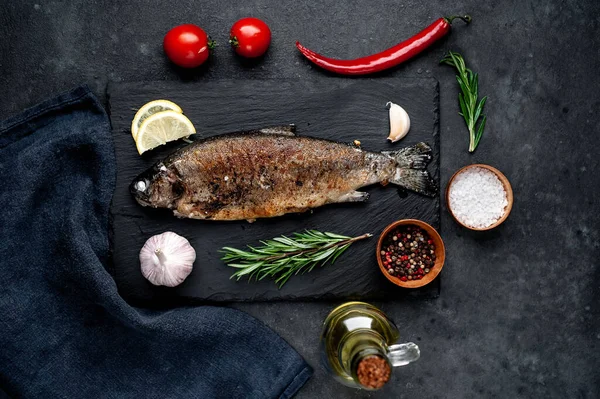 Taş zeminde baharat ve malzemelerle kızarmış balık alabalığı.