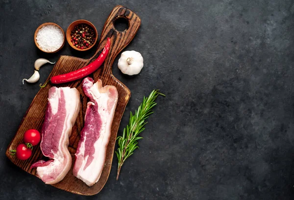 Metnin için fotokopi alanı olan taştan bir arka planda kesilmiş baharatlı çiğ domuz göğsü.