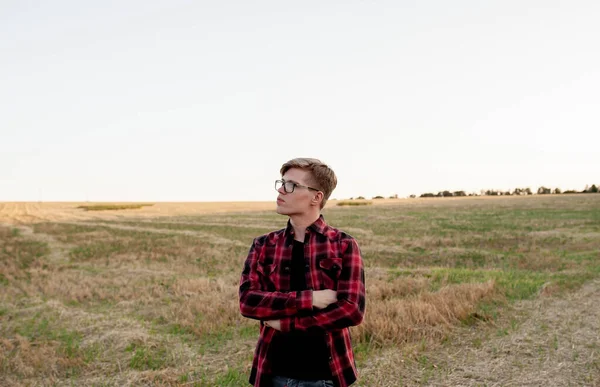 Tişörtlü bir çiftçi gün batımında bir tarlada duruyor.