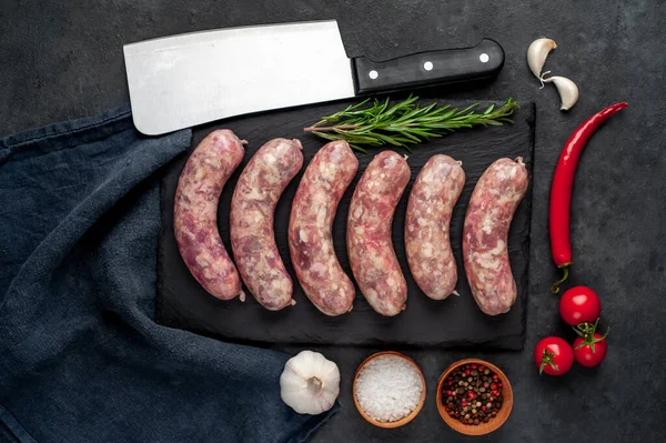Izgara için çiğ sosis ve arka plandaki kesme tahtasındaki baharatlar.