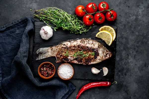 Limonlu ve biberiyeli sazan balığı. Taş zeminde bir tahta üzerinde.