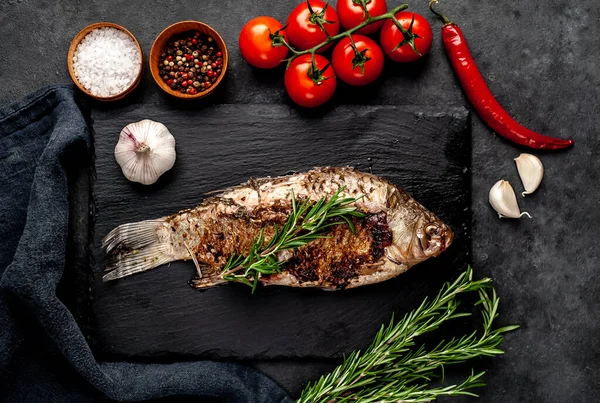 Limonlu ve biberiyeli sazan balığı. Taş zeminde bir tahta üzerinde.